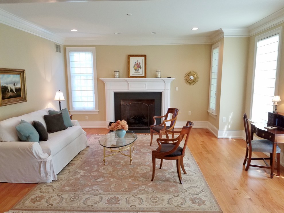 Example of a large transitional enclosed and formal light wood floor and beige floor living room design in Philadelphia with beige walls, a standard fireplace, a plaster fireplace and no tv
