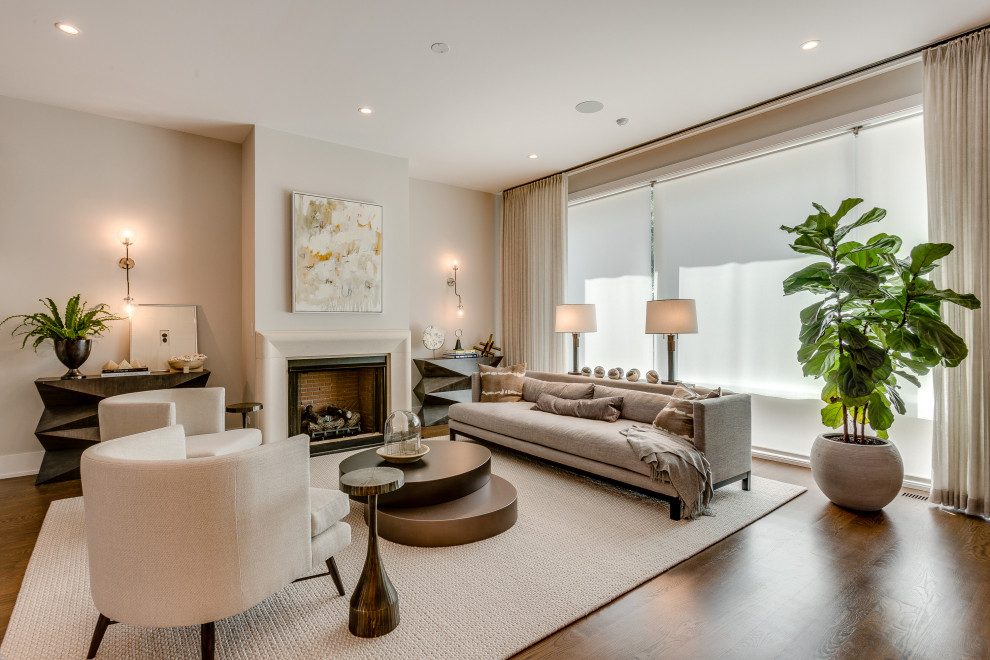 Immagine di un soggiorno design aperto con sala formale, pareti beige, pavimento in legno massello medio, camino classico, nessuna TV e pavimento marrone