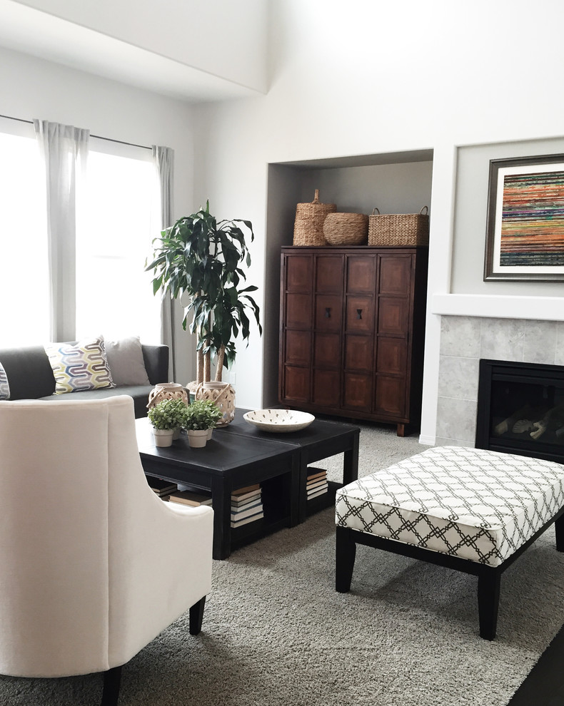 Идея дизайна: открытая гостиная комната среднего размера в стиле неоклассика (современная классика) с серыми стенами, ковровым покрытием, стандартным камином, фасадом камина из плитки и скрытым телевизором