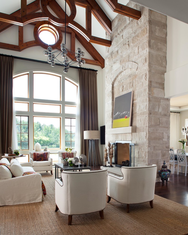 На фото: огромная гостиная комната в стиле неоклассика (современная классика) с темным паркетным полом, стандартным камином и фасадом камина из камня