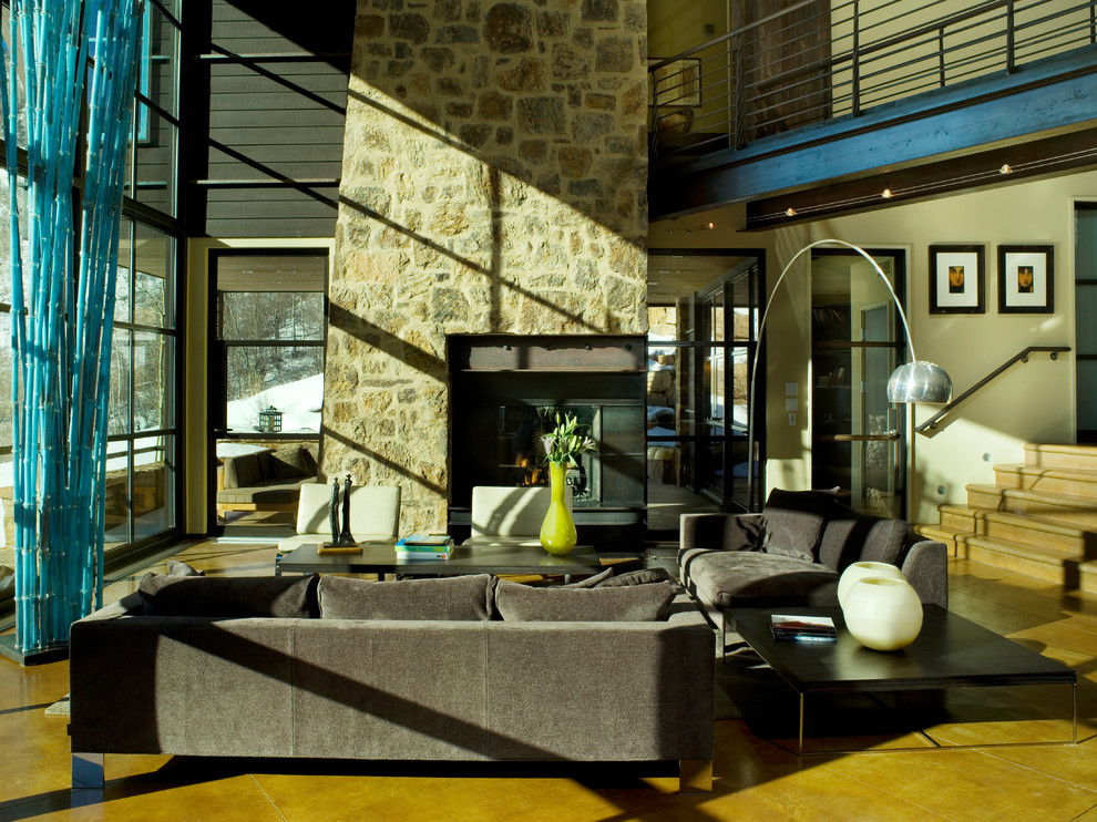 Пример оригинального дизайна: гостиная комната в современном стиле с фасадом камина из камня и коричневым диваном
