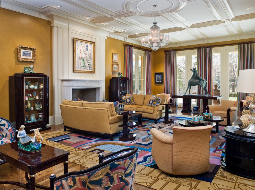 На фото: огромная открытая гостиная комната в классическом стиле с желтыми стенами, деревянным полом, стандартным камином, фасадом камина из камня и ковром на полу без телевизора с