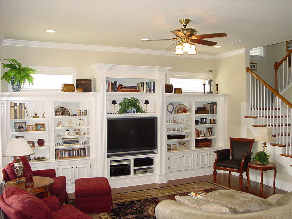 Cette image montre un grand salon traditionnel ouvert avec une salle de réception, un mur beige, un sol en bois brun et un téléviseur encastré.