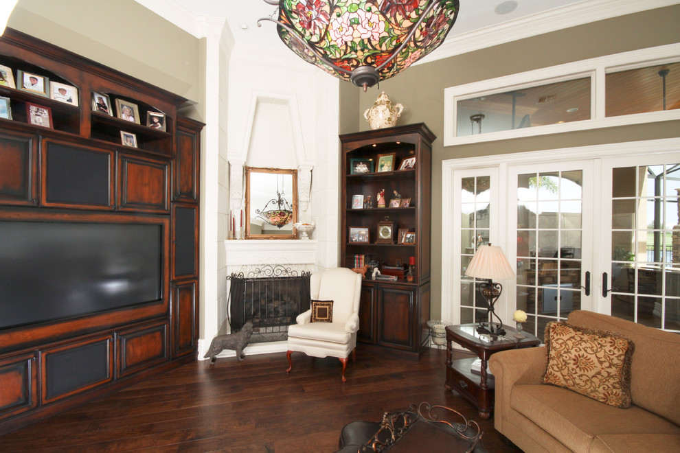 На фото: гостиная комната в классическом стиле с угловым камином и коричневым диваном с