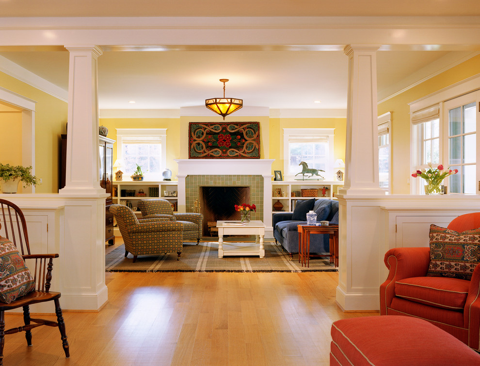 На фото: гостиная комната в классическом стиле с желтыми стенами, светлым паркетным полом, стандартным камином и фасадом камина из плитки