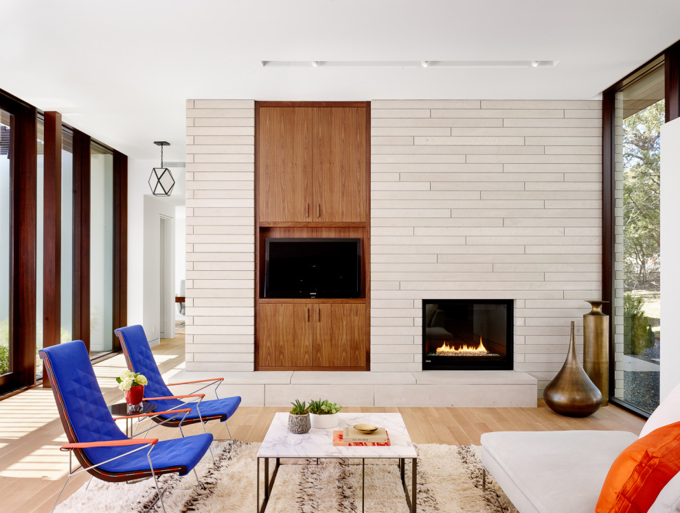 オースティンにある高級な広いミッドセンチュリースタイルのおしゃれなLDK (白い壁、淡色無垢フローリング、標準型暖炉、石材の暖炉まわり、ベージュの床) の写真