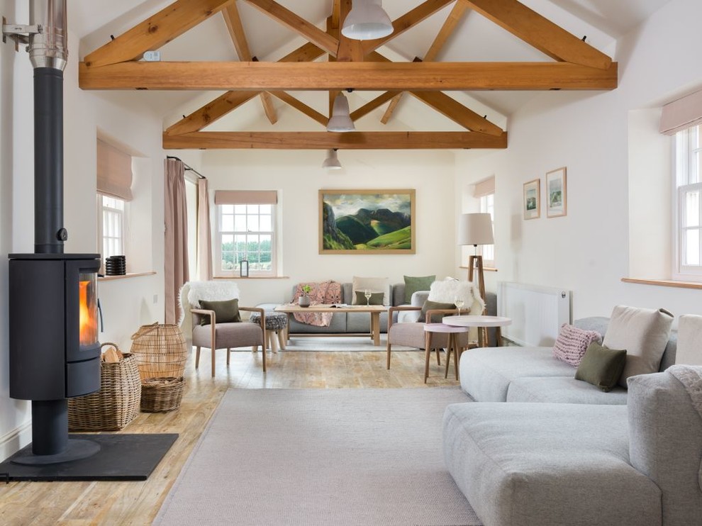 Foto på ett lantligt separat vardagsrum, med vita väggar, ljust trägolv, en öppen vedspis och beiget golv