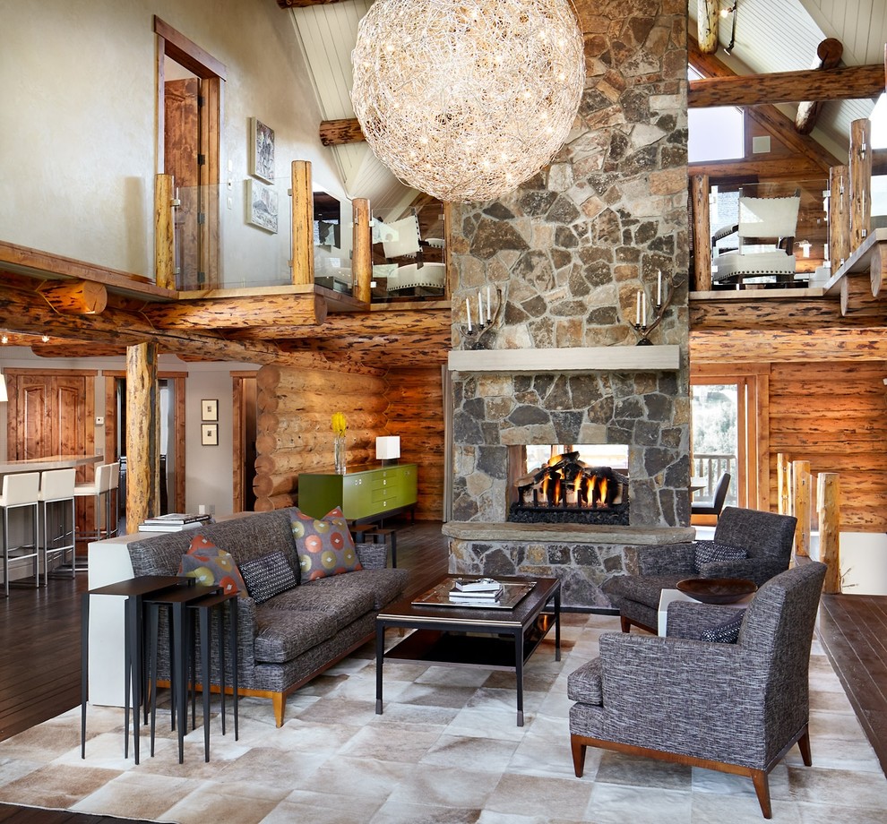 Rustic living room in Denver with dark hardwood flooring, a two-sided fireplace and a stone fireplace surround.