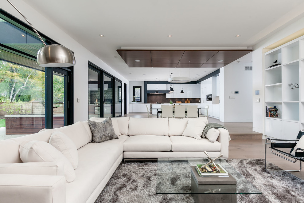 Aménagement d'un grand salon moderne ouvert avec un mur blanc, parquet clair, une cheminée ribbon et un téléviseur encastré.
