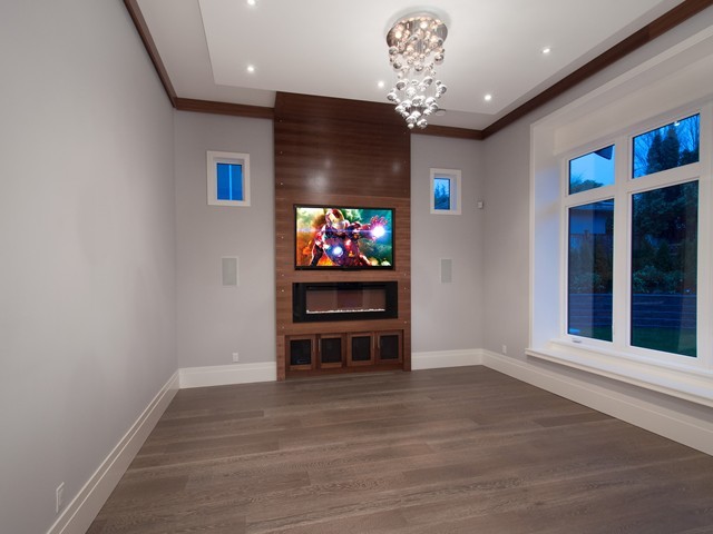 Imagen de salón cerrado tradicional renovado de tamaño medio con paredes grises, suelo de madera en tonos medios, chimenea lineal y televisor colgado en la pared