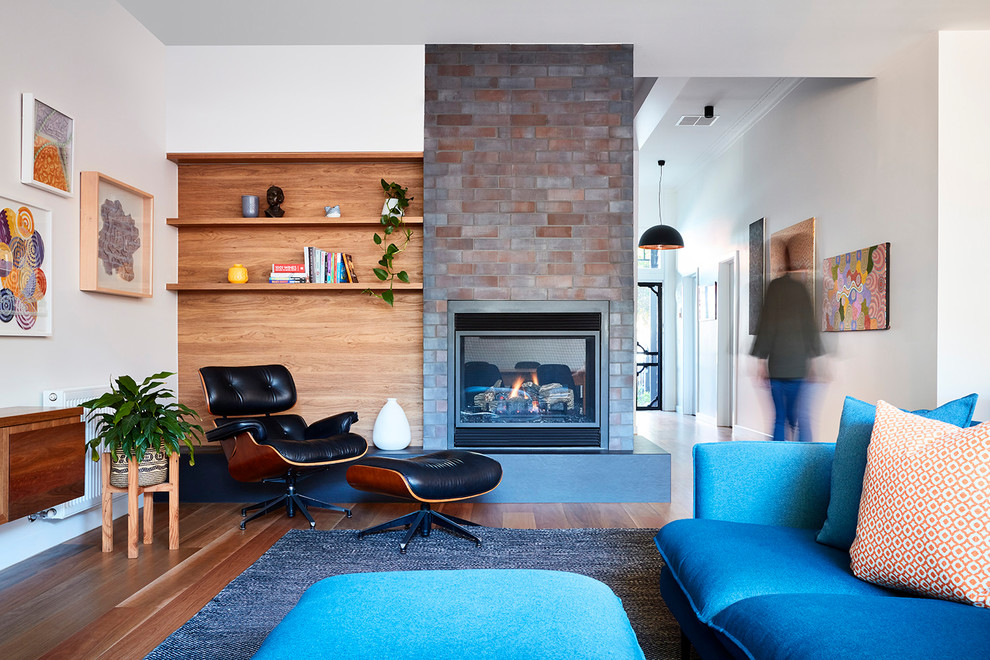 Inspiration pour un petit salon design ouvert avec un sol en bois brun, une cheminée double-face, un manteau de cheminée en brique et un sol marron.