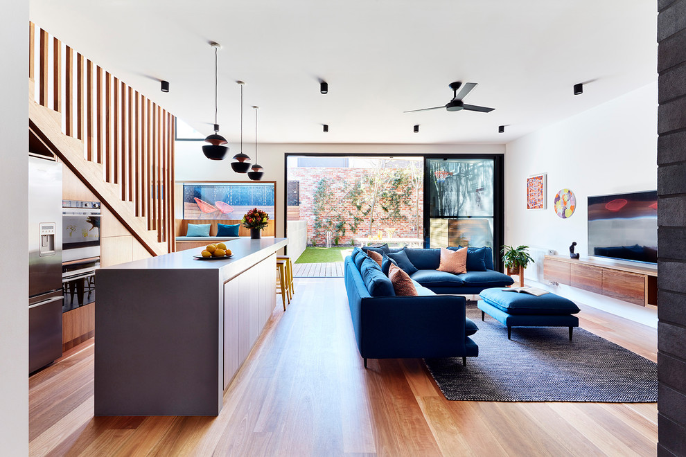 Kleines, Offenes Modernes Wohnzimmer mit braunem Holzboden, Tunnelkamin, Kaminumrandung aus Backstein, braunem Boden, weißer Wandfarbe und TV-Wand in Melbourne