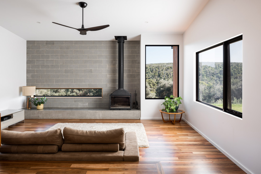 Foto di un soggiorno contemporaneo aperto con pareti bianche, pavimento in legno massello medio, stufa a legna e pavimento marrone
