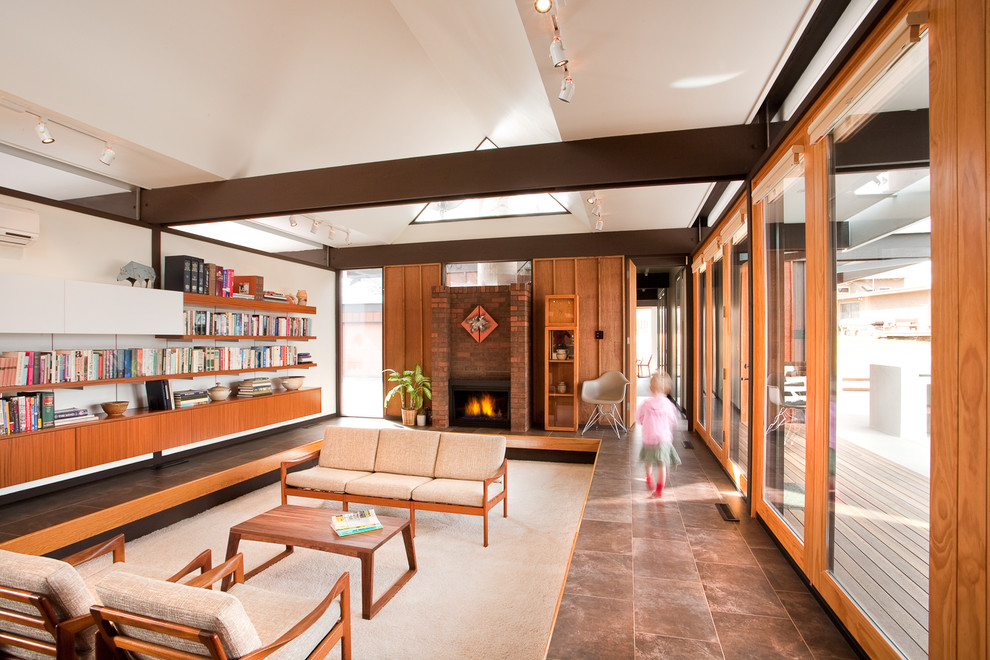 На фото: гостиная комната в стиле модернизм с с книжными шкафами и полками и стандартным камином с