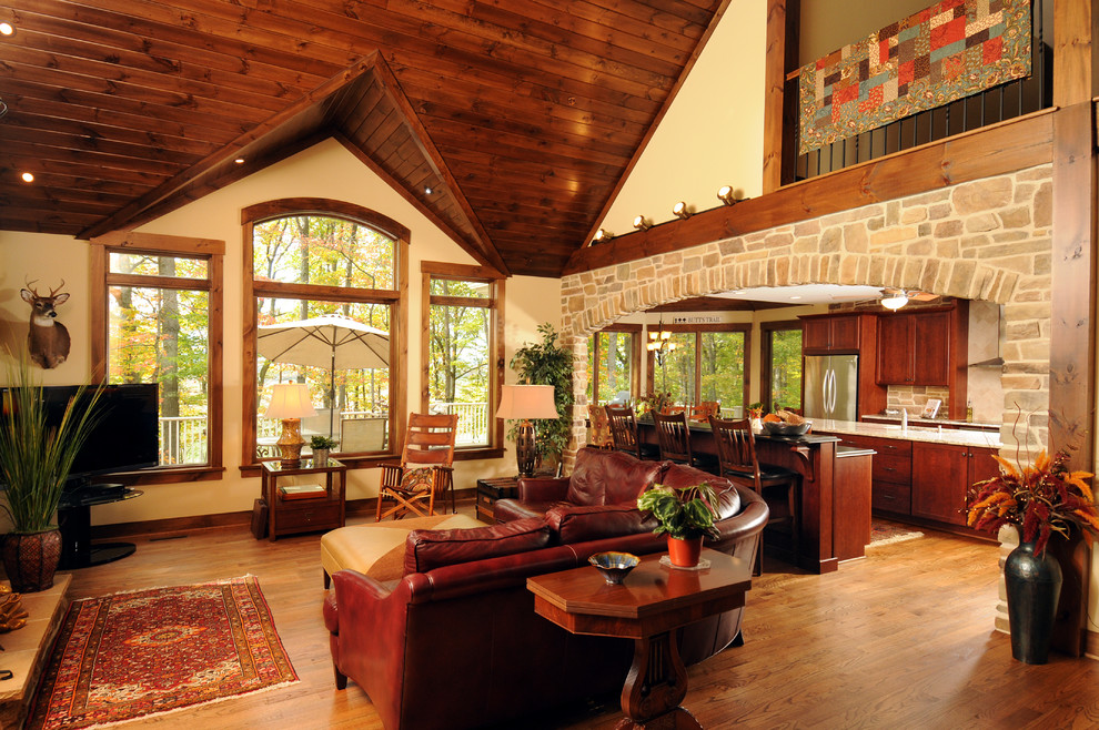 Foto de salón abierto rural con suelo de madera en tonos medios, televisor independiente, arcos y piedra