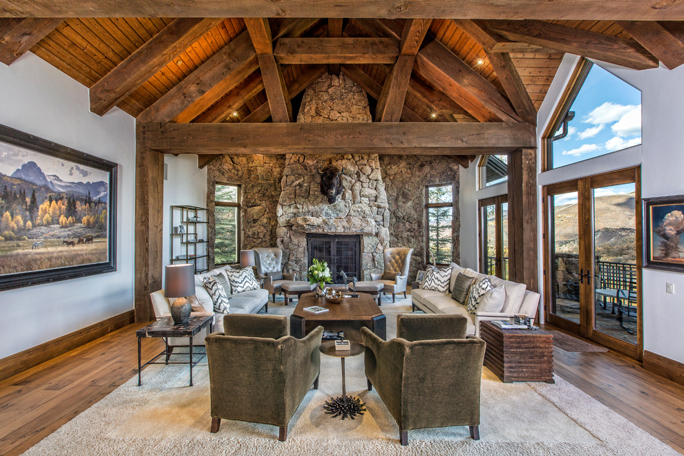 Example of a large mountain style open concept dark wood floor and brown floor living room design in Denver with gray walls, a standard fireplace, a stone fireplace and no tv