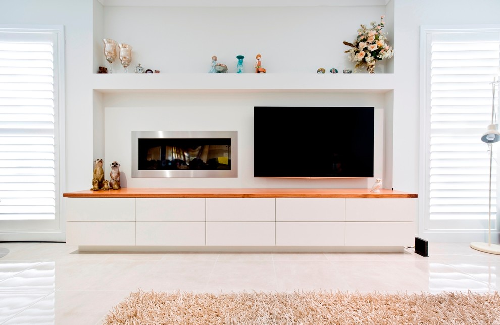 Cette image montre un salon design avec un mur blanc, un sol en carrelage de céramique, un manteau de cheminée en métal, un téléviseur fixé au mur et une cheminée ribbon.