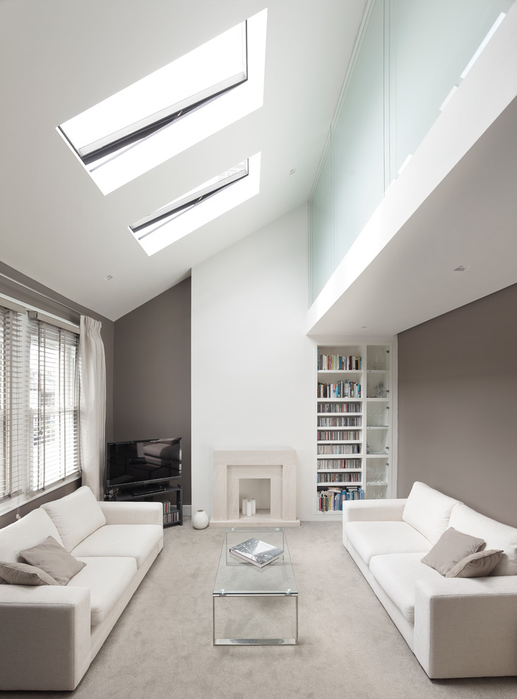 Offenes Modernes Wohnzimmer mit grauer Wandfarbe, Teppichboden, Kamin, Kaminumrandung aus Stein und freistehendem TV in London