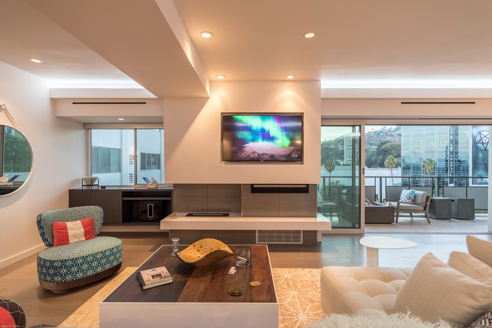 Large contemporary open plan living room in Los Angeles with white walls, light hardwood flooring, a tiled fireplace surround, a built-in media unit and beige floors.
