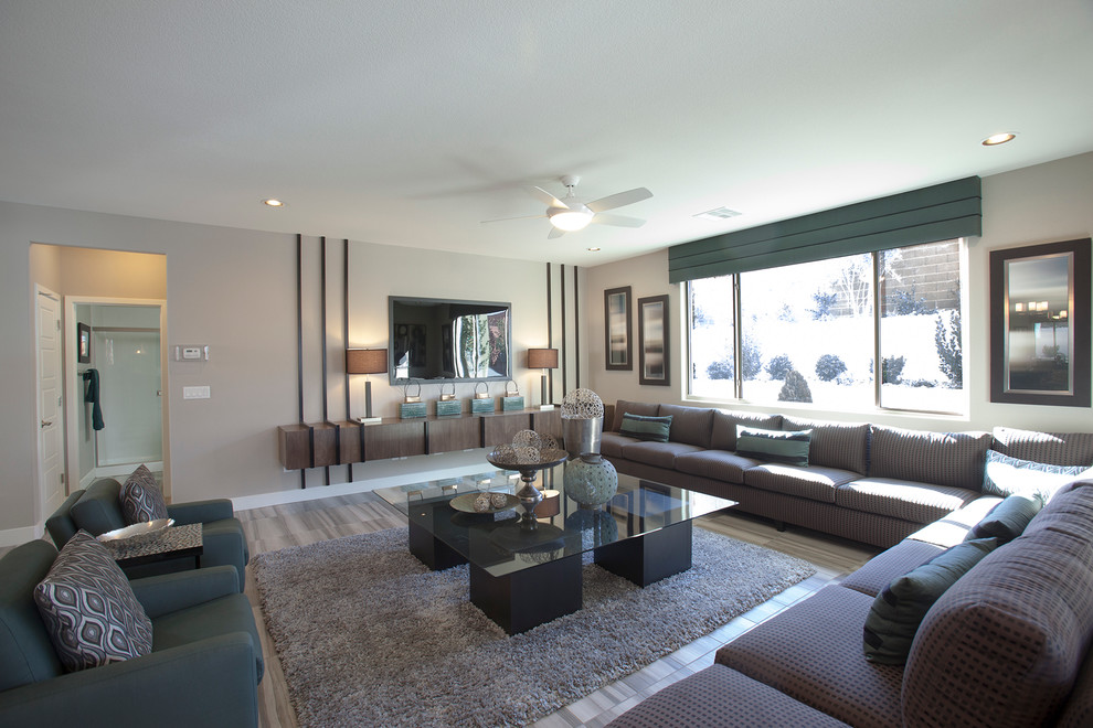 Diseño de salón abierto actual grande sin chimenea con paredes grises, suelo de madera en tonos medios, televisor colgado en la pared y suelo beige