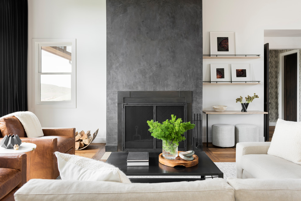 他の地域にあるコンテンポラリースタイルのおしゃれなLDK (白い壁、漆喰の暖炉まわり、茶色い床、無垢フローリング、標準型暖炉) の写真