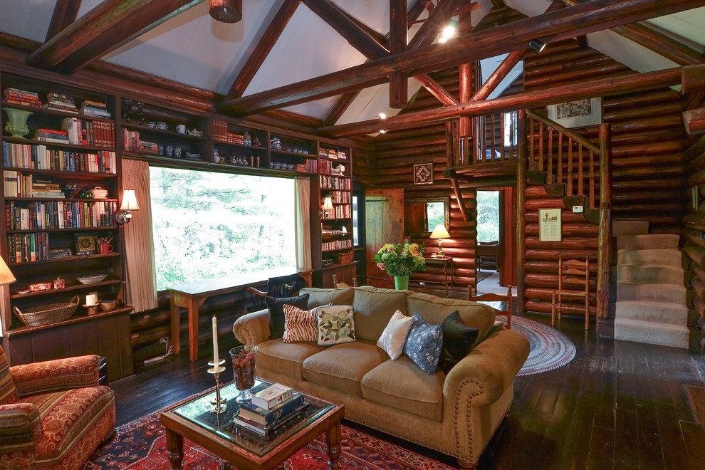 Immagine di un soggiorno stile rurale di medie dimensioni e stile loft con pareti marroni, parquet scuro, camino classico, cornice del camino in pietra e nessuna TV