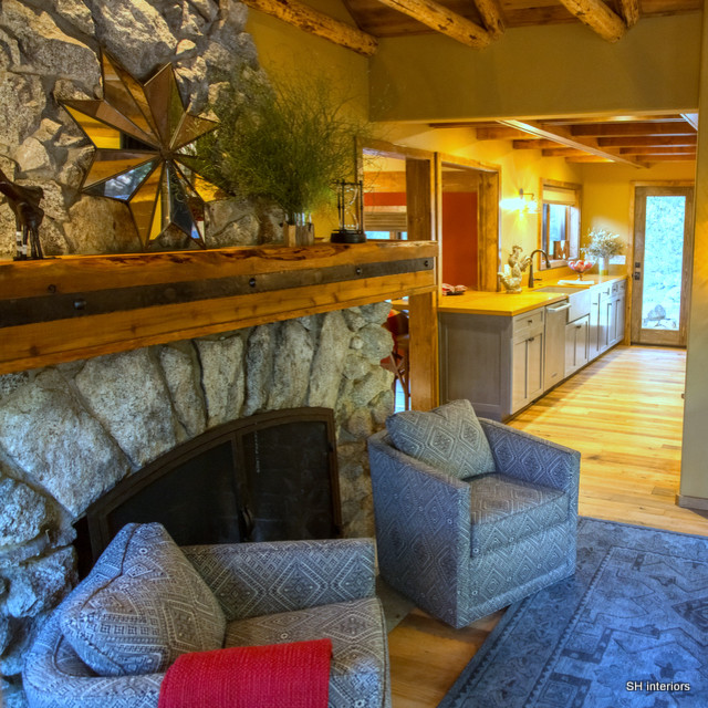 Immagine di un piccolo soggiorno rustico chiuso con pavimento in legno massello medio, camino bifacciale, cornice del camino in pietra e TV a parete