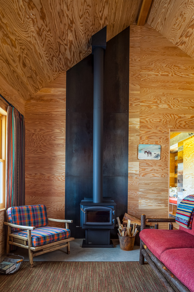 Esempio di un piccolo soggiorno rustico chiuso con stufa a legna, cornice del camino in metallo, nessuna TV e pareti marroni