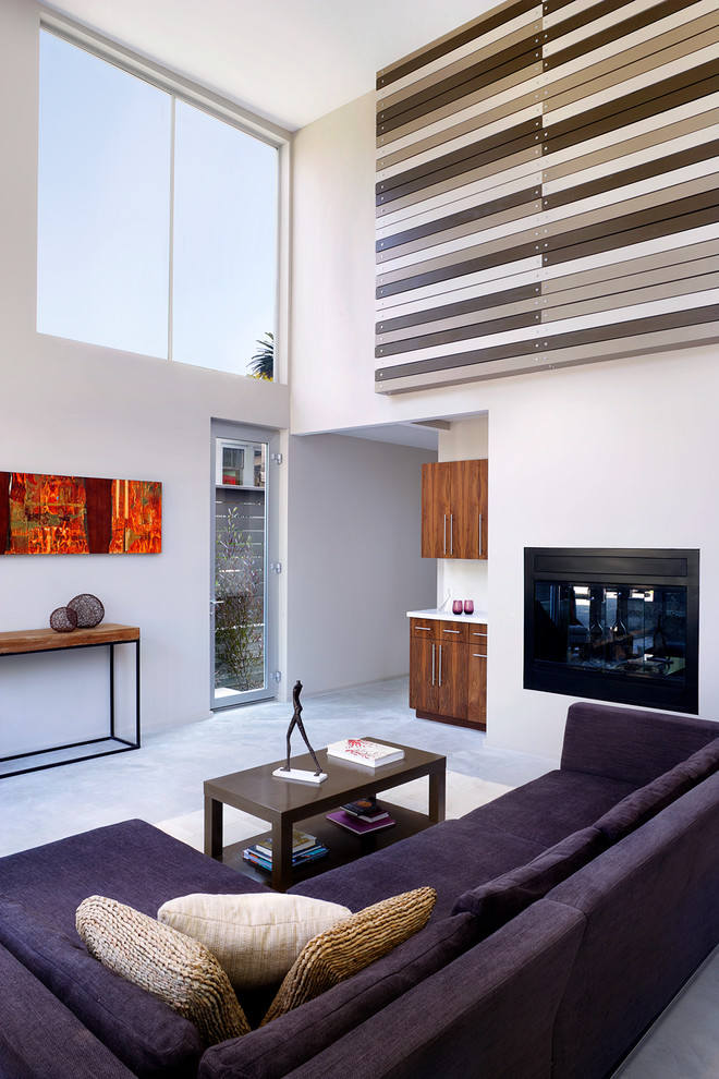 Cette image montre un salon design de taille moyenne et ouvert avec une salle de réception, une cheminée standard, un mur blanc, sol en béton ciré et un téléviseur encastré.