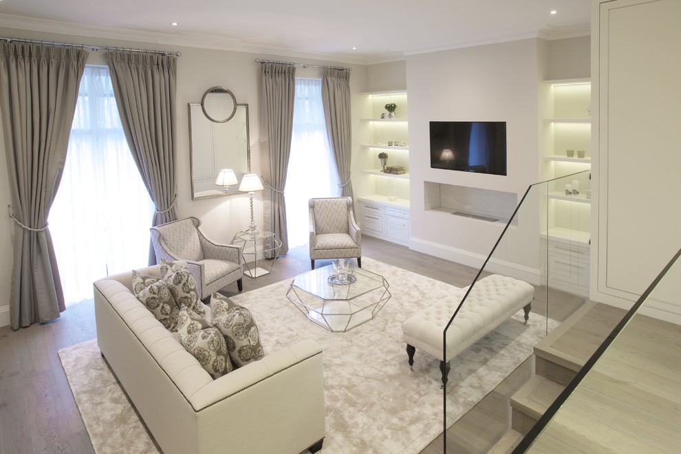 На фото: гостиная комната в стиле неоклассика (современная классика) с белыми стенами, светлым паркетным полом, горизонтальным камином, телевизором на стене и серым полом