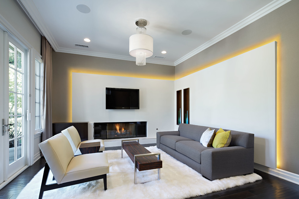 Modelo de salón para visitas abierto contemporáneo grande con paredes grises, suelo de madera oscura, chimenea lineal, televisor colgado en la pared y alfombra