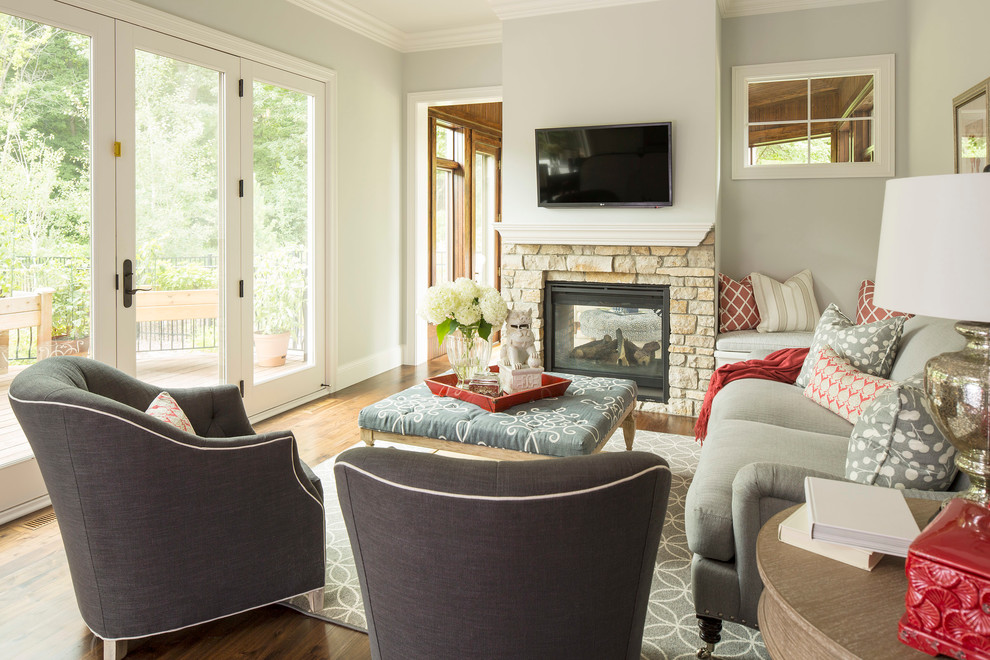 Example of a transitional medium tone wood floor living room design in Minneapolis with gray walls, a two-sided fireplace and a stone fireplace