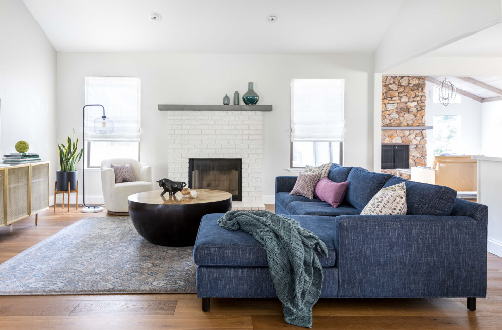 Example of a large transitional open concept medium tone wood floor and brown floor living room design in Sacramento with gray walls, a standard fireplace, a stone fireplace and no tv