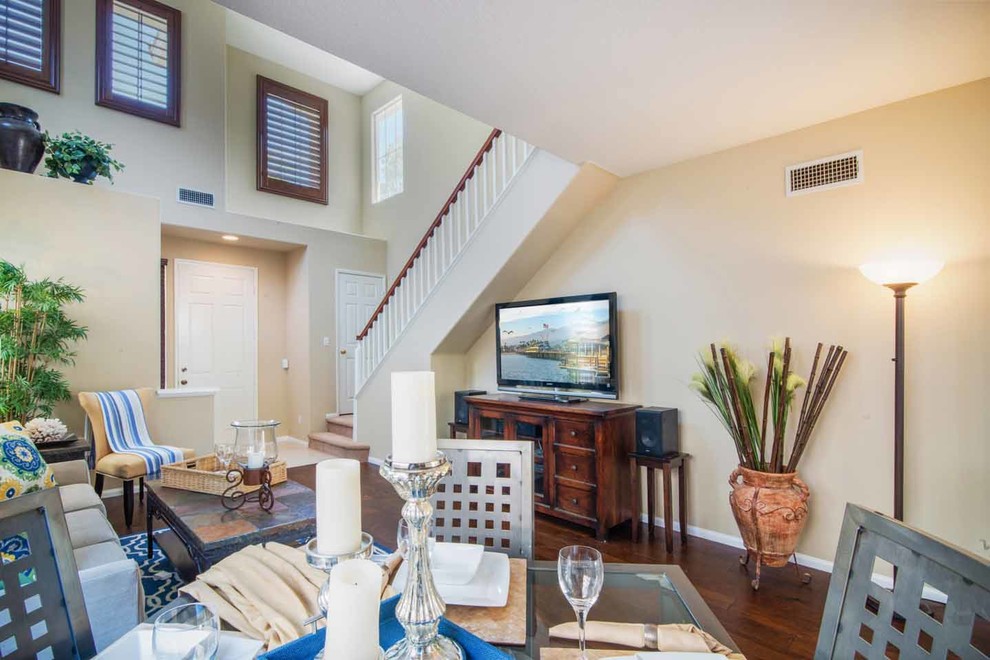 Maritimes Wohnzimmer mit beiger Wandfarbe, braunem Holzboden und freistehendem TV in Los Angeles