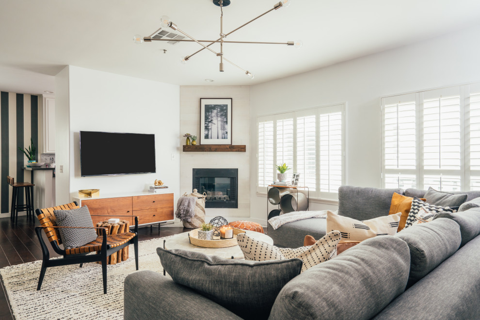 Immagine di un soggiorno minimal aperto con pareti bianche, parquet scuro, camino classico, TV a parete e pavimento marrone