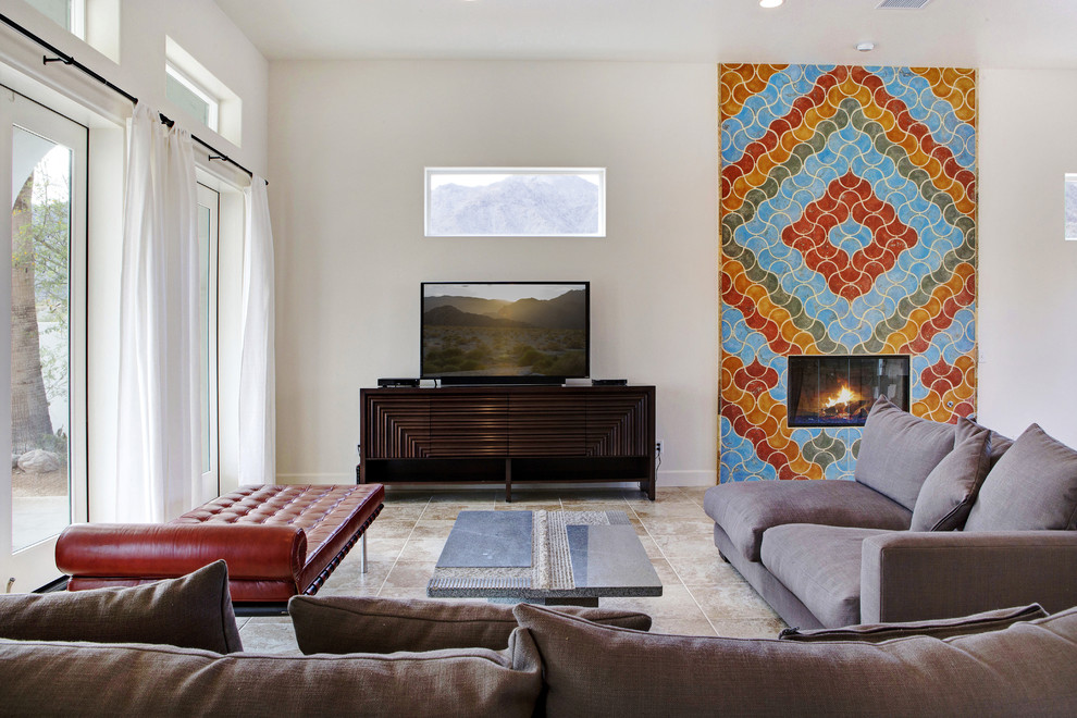ロサンゼルスにある高級な広い地中海スタイルのおしゃれなLDK (白い壁、コンクリートの床、標準型暖炉、タイルの暖炉まわり、据え置き型テレビ) の写真
