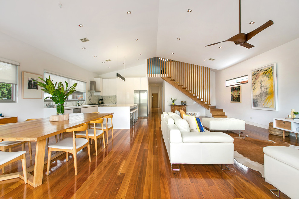 Ejemplo de salón abierto contemporáneo de tamaño medio con paredes blancas y suelo de madera en tonos medios