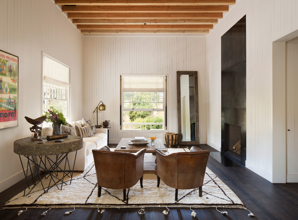 Inspiration for a country living room in Other with white walls, dark hardwood flooring, a standard fireplace and brown floors.