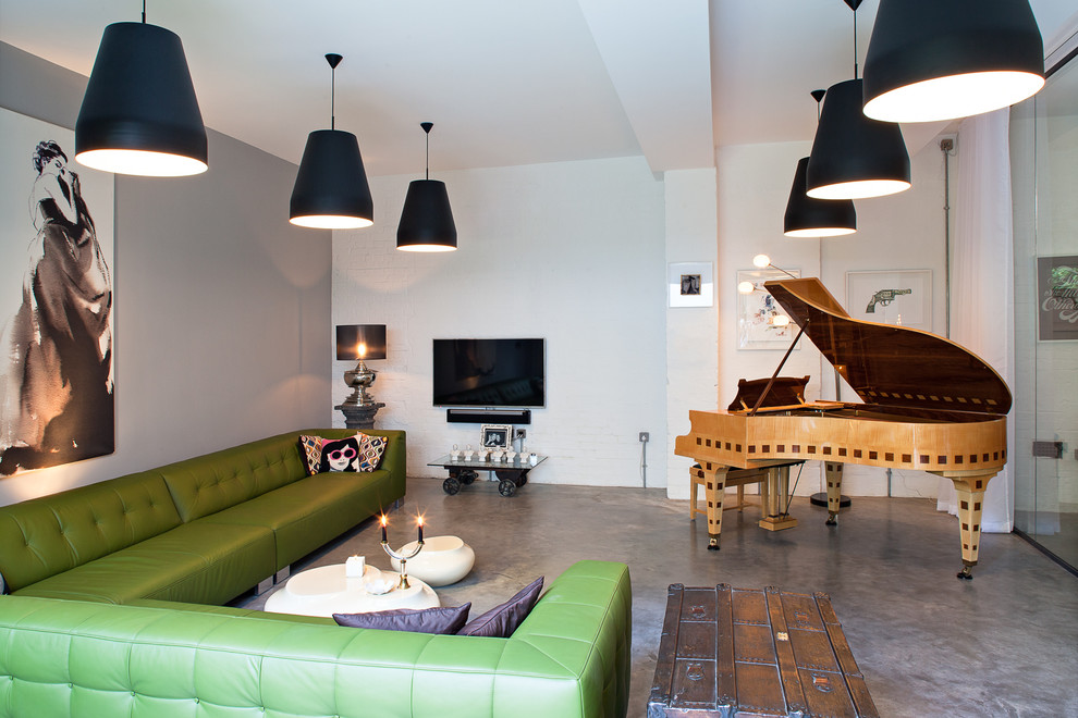 На фото: гостиная комната в стиле лофт с музыкальной комнатой, белыми стенами, бетонным полом и телевизором на стене с