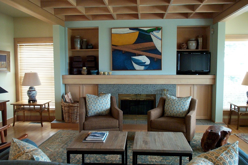 Ejemplo de salón abierto costero de tamaño medio con paredes azules, suelo de madera clara, todas las chimeneas, marco de chimenea de hormigón y pared multimedia