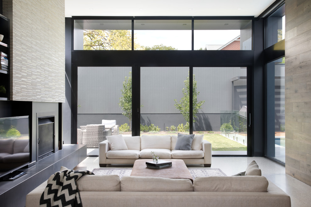 Idee per un grande soggiorno moderno aperto con pareti nere, pavimento in cemento, camino classico, cornice del camino piastrellata e TV autoportante