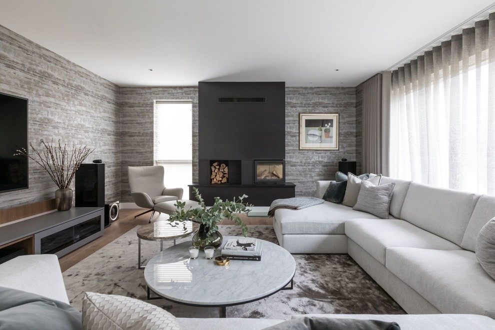 Inspiration pour un grand salon design avec un mur gris, un sol en bois brun, un poêle à bois, un manteau de cheminée en métal, un téléviseur fixé au mur et un sol beige.