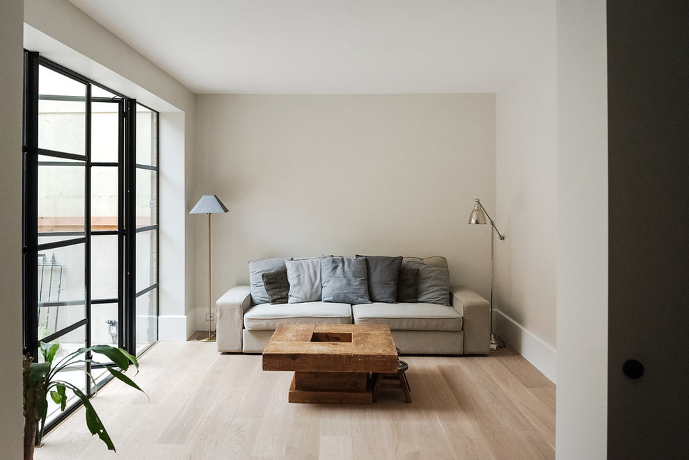 Modelo de salón para visitas abierto moderno de tamaño medio con paredes blancas, suelo de madera clara y suelo marrón