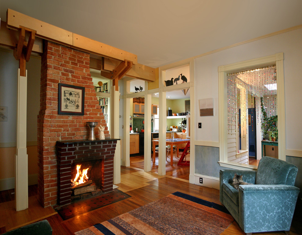 Photo of a medium sized eclectic enclosed living room in Boston with dark hardwood flooring, a standard fireplace, a brick fireplace surround, white walls and no tv.