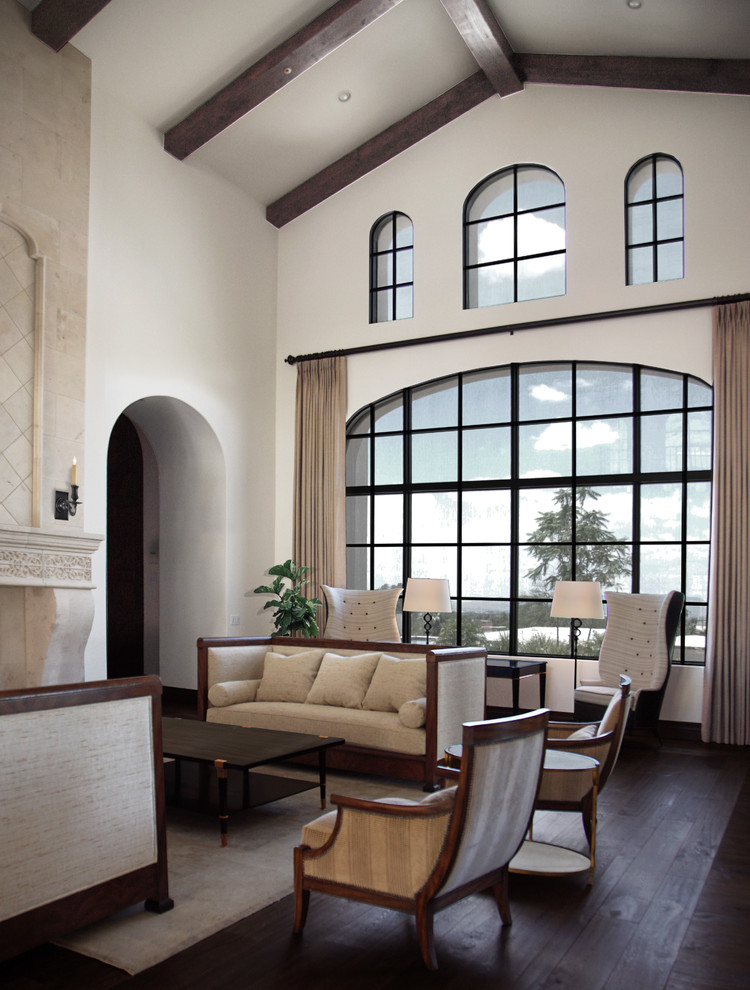 Пример оригинального дизайна: большая открытая гостиная комната с белыми стенами, темным паркетным полом, коричневым полом, сводчатым потолком, стандартным камином и фасадом камина из камня