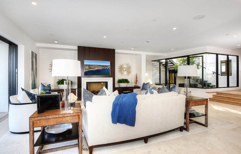 Стильный дизайн: большая открытая гостиная комната в морском стиле с стандартным камином, телевизором на стене, белыми стенами, полом из керамической плитки и бежевым полом - последний тренд