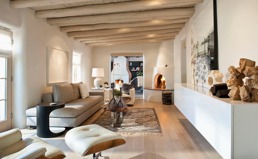 Example of a mid-sized southwest enclosed light wood floor living room design in Albuquerque with a corner fireplace, white walls and a plaster fireplace