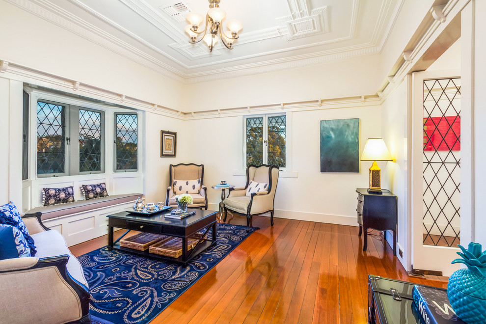Imagen de salón para visitas cerrado clásico sin televisor con paredes blancas y suelo de madera en tonos medios