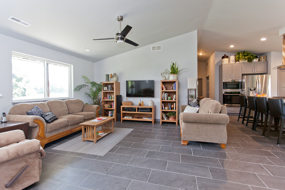 На фото: открытая гостиная комната в классическом стиле с серыми стенами, полом из керамической плитки, телевизором на стене и серым полом