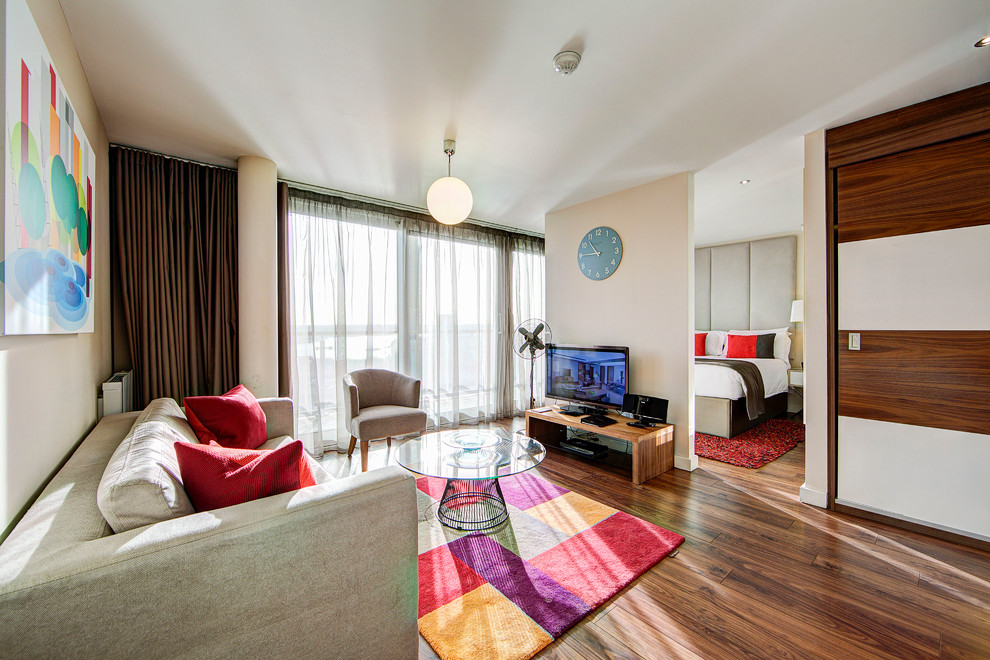 Immagine di un grande soggiorno minimalista aperto con sala formale, pareti bianche, pavimento in legno massello medio, nessun camino e TV autoportante